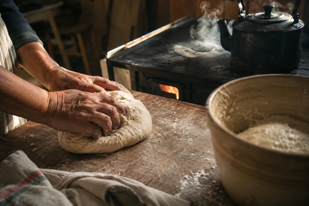 Hands kneading bread by a wood stove